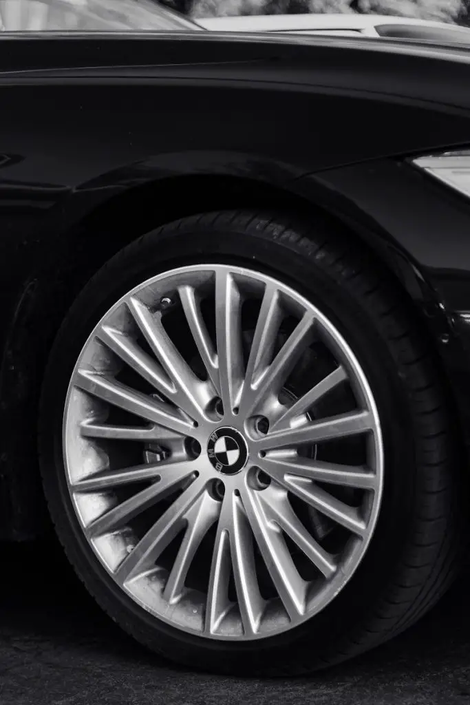 Detailed shot of a luxury car wheel in monochrome, showcasing design elegance.