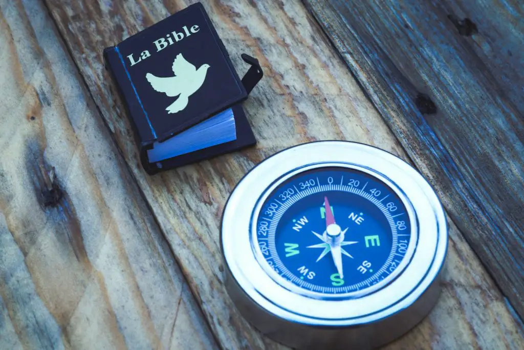 round silver compass beside La Bible