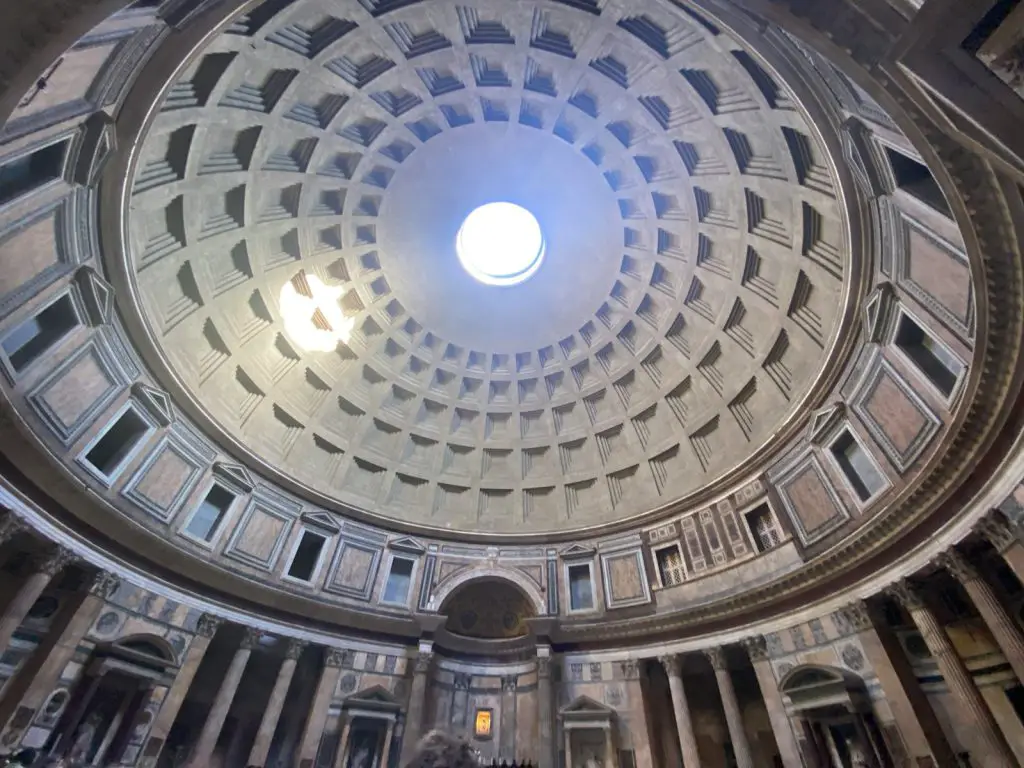 a circular ceiling with a light with Pantheon, Rome in the background